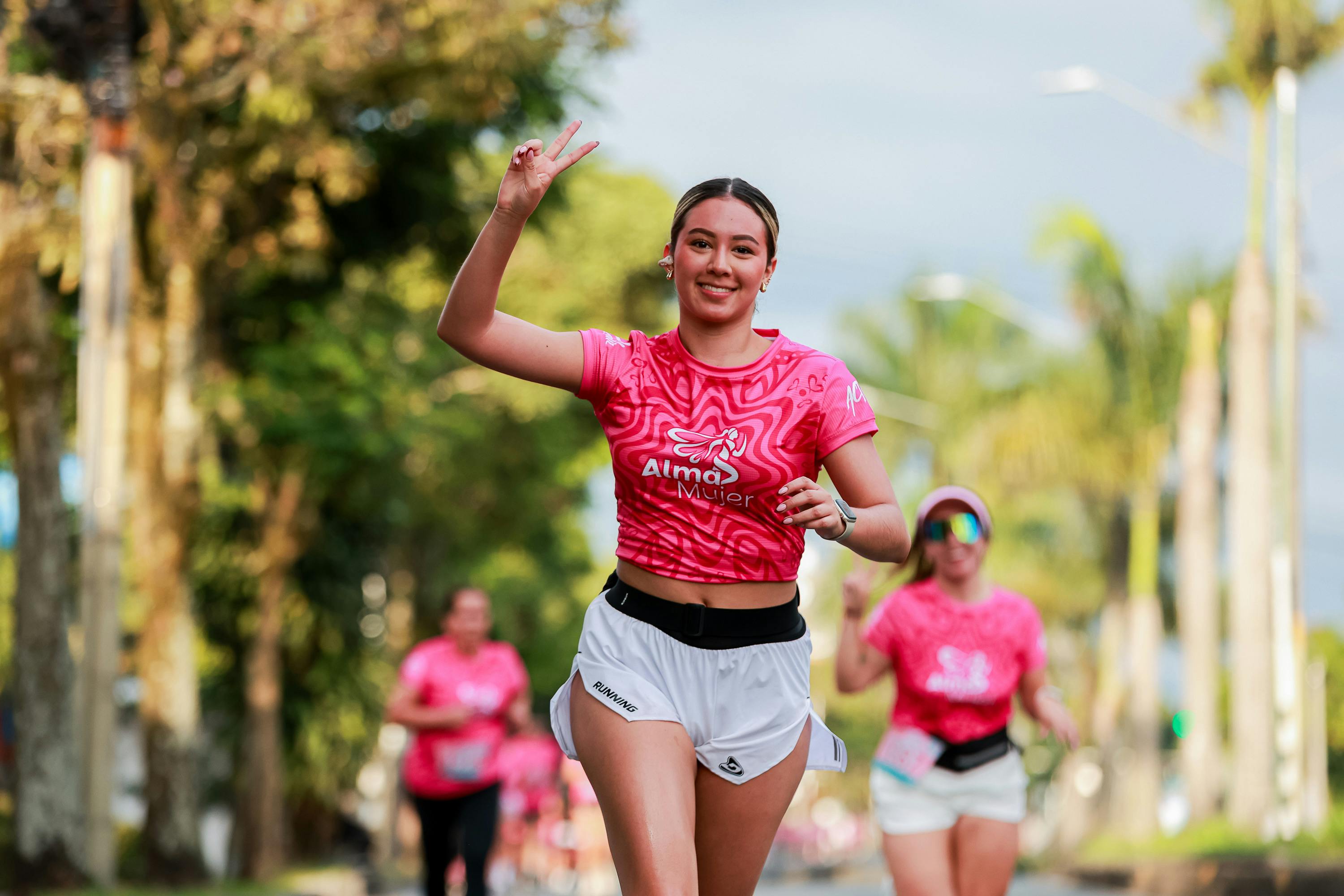 Woman running in a race smiling after seeing the Sports Injuries specialist in Guatemala